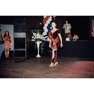 Damaris Padilla walks across the floor wearing a Villalba sash at the Festival Puertorriqueño