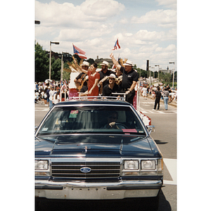 A car pulls a float holding several people during a Festival Puertorriqueño parade