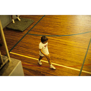 Child walking across a gymnasium floor