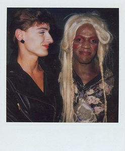 A Photograph of Marsha P. Johnson With Blonde Hair and Red Eyeshadow, Next to Another Person