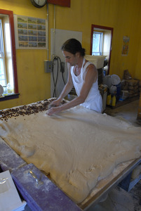 Hungry Ghost Bread: owner and baker Jonathan C. Stevens working spreading raisins on dough for cinnamon rolls