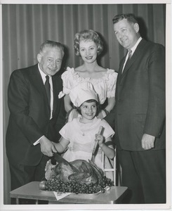 Abe Stark, Candace Hilligoss and Willis C. Gorthy carving a turkey with young client.