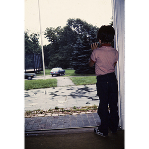 Boy looking outside from the entrance to a building