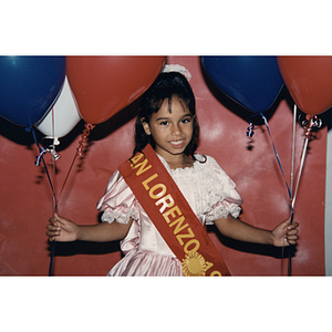 A girl wearing a San Lorenzo sash smiles for the camera at the Festival Puertorriqueño