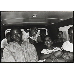 A group of children laugh and make funny faces in a van