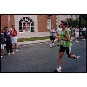 A woman runs during the Bunker Hill Road Race as spectators look on