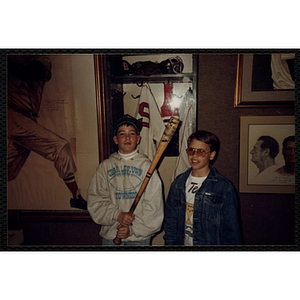 Two boys pose with a bat in front of an exhibit of the Red Sox's Ted Williams' locker at the New England Sports Museum