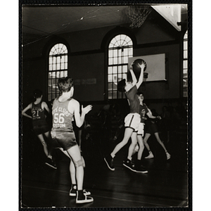 A boy grabs a rebound during an indoor basketball game