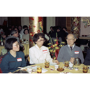 Henry Wong sits with two women at a restaurant table during a celebration of the Chinese New Year