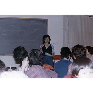 Teacher lectures at the front of listening students