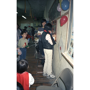 Children play "pin the tail on the donkey" with balloons at a Chinese Progressive Association celebration