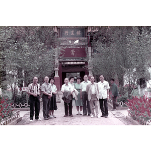 Association members stand in front of a large gateway in a botanical garden