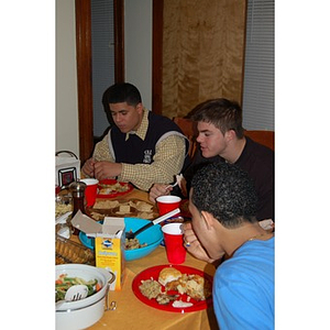 Three students eat at the Torch Scholars Thanksgiving Dinner