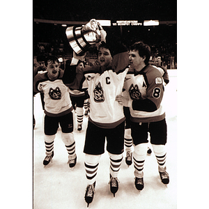 Three Northeastern hockey players skate with the Beanpot trophy