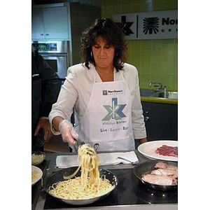 A woman cooks when the Torch Scholars visit the Exhibition Kitchen