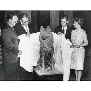 Four people unveil the Husky statue