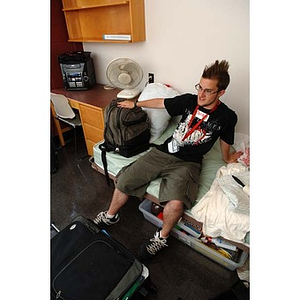 Jordan Munson sits with his things on his bed during move-in