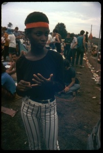 Young African American woman with a headband and striped pants at the Woodstock Festival