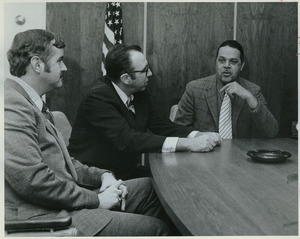 Randolph W. Bromery sitting indoors conversing with two men