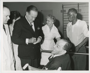 Bob Hope signing autograph for patient in wheelchair