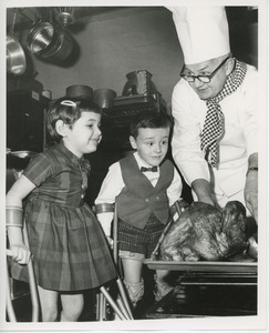 Children watching chef pull turkey out of oven