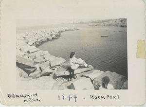 Bernice Kahn seated on rocks at shoreline of Bearskin Neck