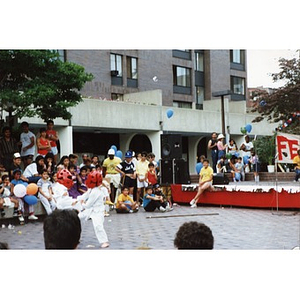 Two young Latino children give a karate demonstration while a crowd of people watches in the Plaza Betances, during the Festival Betances, 1986