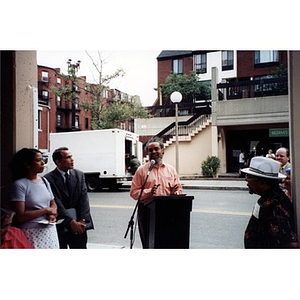 Man at an outdoor podium addressing participants at the unveiling of the Villa Victoria historic markers.