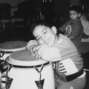 Little boy resting his head on a conga drum.