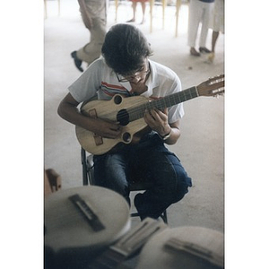 Young man playing a small guitar or cuatro.