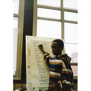 Boy writing on a flip chart during a Teen and Kid Empowerment Program class.
