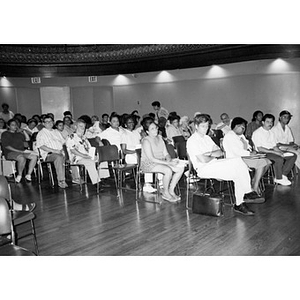 Villa Victoria community members sitting in rows in the Jorge Hernandez Cultural Center for a community meeting.