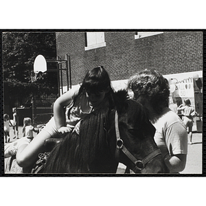 A girl sits on a pony at a carnival