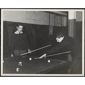 Two teenage boys playing a game of pool