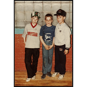 Three boys standing in front of a wall at an open house event