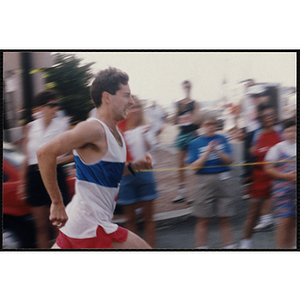 A man runs past spectators during the Bunker Hill Road Race as spectators look on