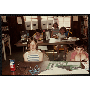 A Group of children sitting at tables next to their science fair projects