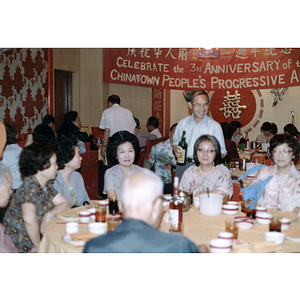 Henry Wong socializes at a restaurant table at Chinese Progressive Association's Third Anniversary Celebration