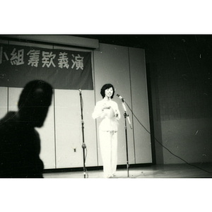 Woman sings at a microphone on stage during a performance for the Chinatown Task Force Fundraiser