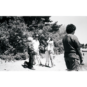 Three Association members and a girl converse on a beach, at a Chinese Progressive Association picnic
