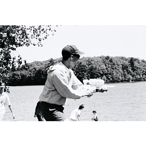 Young man shoots a water gun at a lake