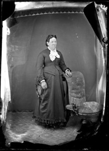 Full length portrait of a woman standing next to a chair