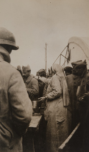 Red Cross worker serving food to a crowd of soldiers