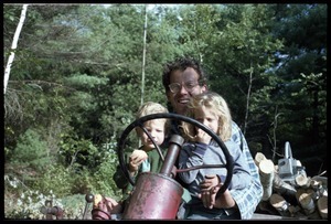 Daniel Keller driving a tractor with two children, Montague Farm commune