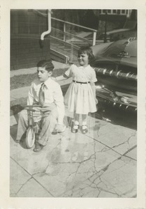 Paul Kahn seated on a tricycle with his sister Sharon standing behind