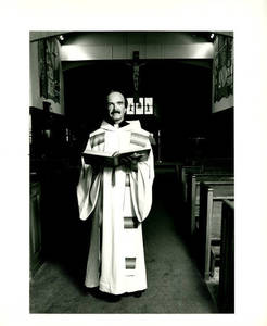 Father Leo Hoar in a Chapel holding a Bible