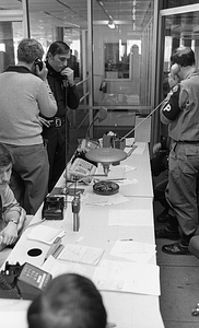 Unidentified officer, Military Police officer, and others using telephones in Boston Police Dispatch Operations Center