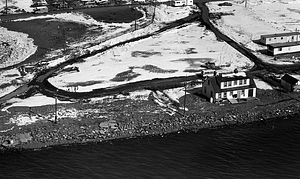 Aerial view of house, beach, and water covered in snow