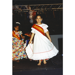 A girl wearing a Bayamon sash and white dress at the Festival Puertorriqueño