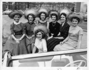 Women wearing straw hats in a convertible, 1957